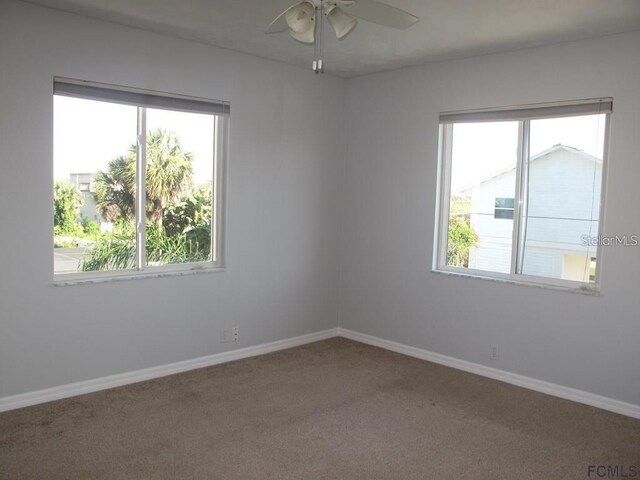 empty room with carpet floors, ceiling fan, plenty of natural light, and baseboards