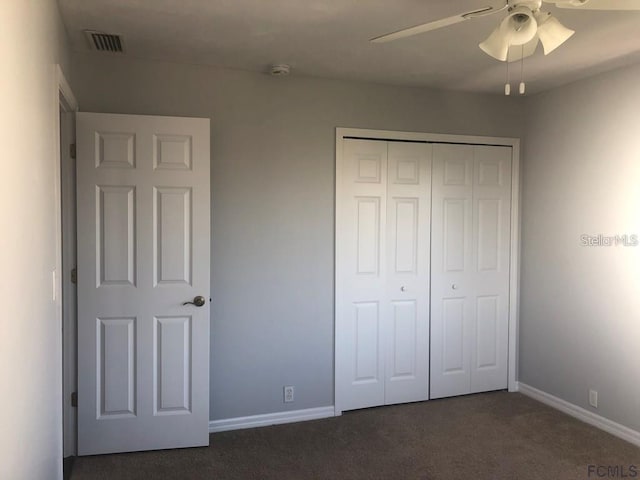 unfurnished bedroom featuring dark carpet, a closet, baseboards, and a ceiling fan