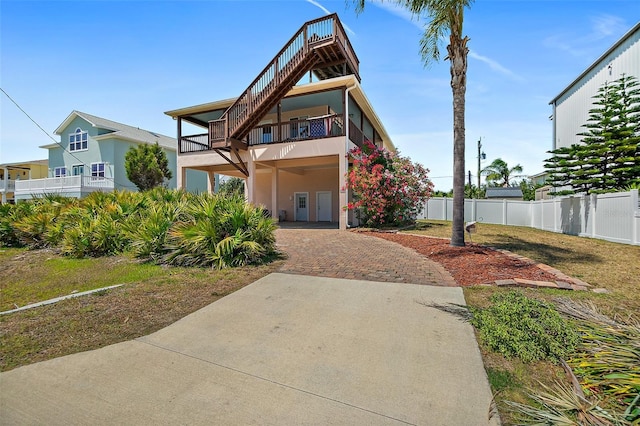 view of front of home with a balcony, fence, stucco siding, and driveway