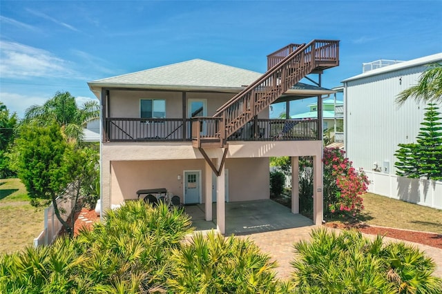 rear view of property with stairs, stucco siding, and a carport