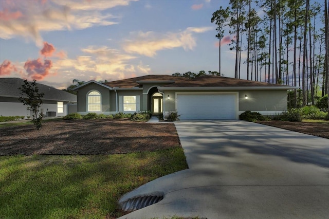 view of front of property featuring an attached garage, concrete driveway, and stucco siding