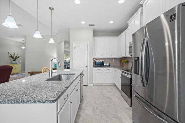 kitchen featuring appliances with stainless steel finishes, a sink, a center island with sink, decorative backsplash, and white cabinetry