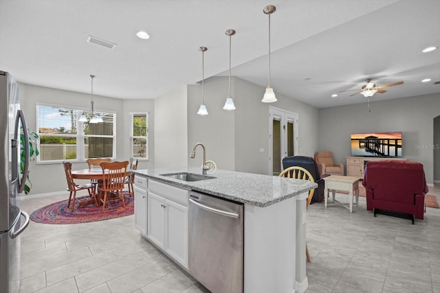 kitchen with a sink, stainless steel appliances, light stone counters, recessed lighting, and hanging light fixtures