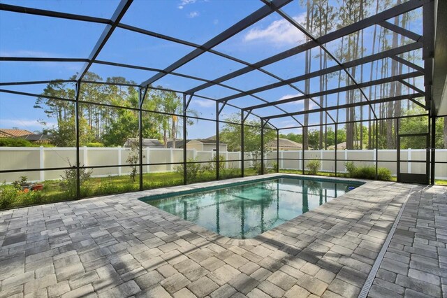 view of swimming pool featuring a patio area, a fenced backyard, and glass enclosure