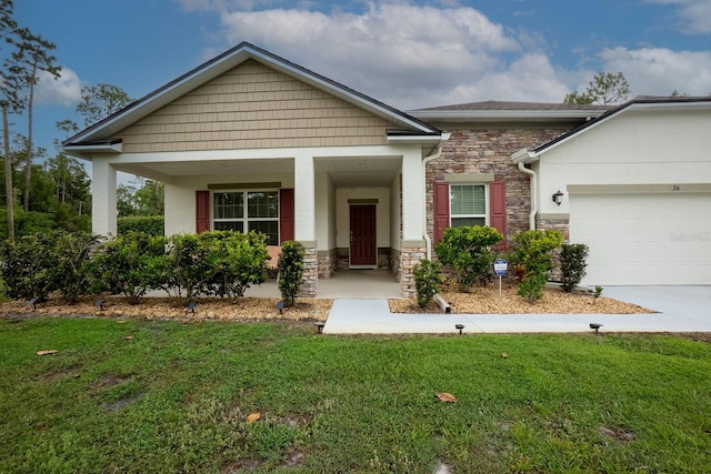 craftsman-style home featuring stone siding, a front yard, driveway, an attached garage, and a porch