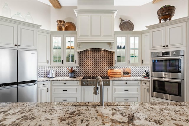 440 Lambert Ave, Flagler Beach, FL 32136 - kitchen with appliances with stainless steel finishes, light stone counters, decorative backsplash, and glass insert cabinets