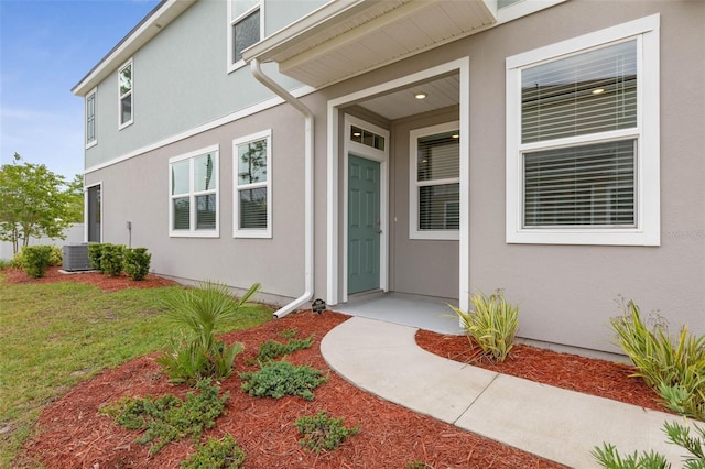 155 Redbud Rd, Palm Coast, FL 32137 - property entrance featuring stucco siding, central air condition unit, and a yard