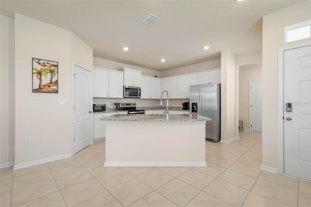 155 Redbud Rd, Palm Coast, FL 32137 - kitchen with stainless steel appliances, an island with sink, light stone countertops, white cabinets, and light tile patterned floors