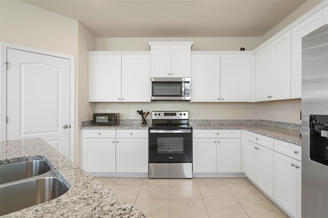 155 Redbud Rd, Palm Coast, FL 32137 - kitchen featuring stainless steel appliances, white cabinetry, light tile patterned floors, and light stone counters