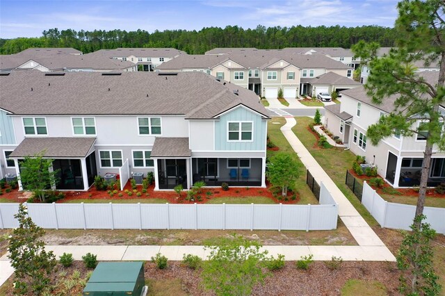 155 Redbud Rd, Palm Coast, FL 32137 - back of house featuring a shingled roof, a residential view, board and batten siding, a fenced backyard, and a sunroom