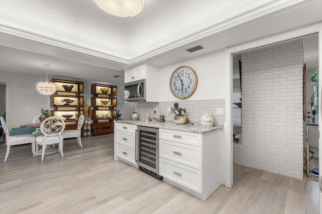 940 Lambert Ave, Flagler Beach, FL 32136 - bar area featuring beverage cooler, light wood-style floors, stainless steel microwave, brick wall, and decorative backsplash