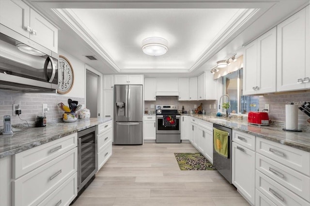 940 Lambert Ave, Flagler Beach, FL 32136 - kitchen featuring stainless steel appliances, wine cooler, a tray ceiling, a sink, and backsplash