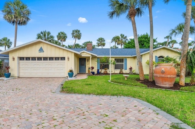 940 Lambert Ave, Flagler Beach, FL 32136 - ranch-style house with a chimney, a front lawn, a garage, and driveway