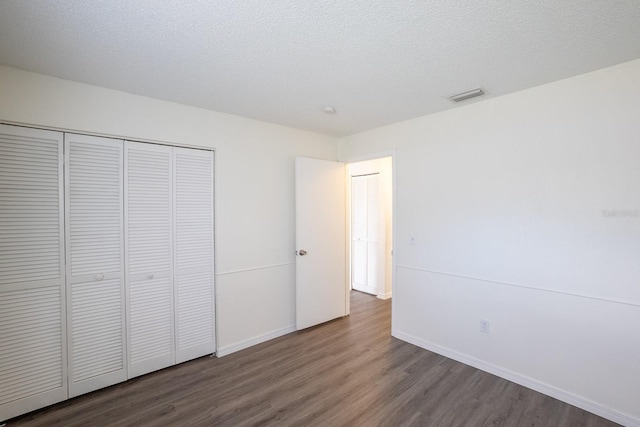 unfurnished bedroom with wood finished floors, a closet, and baseboards