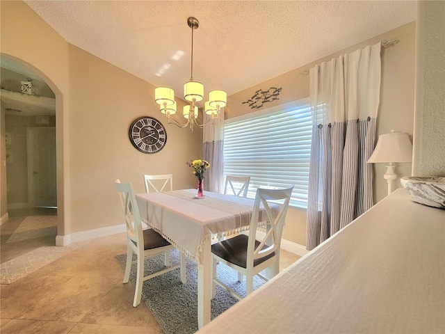 dining room featuring arched walkways, a chandelier, a textured ceiling, and baseboards