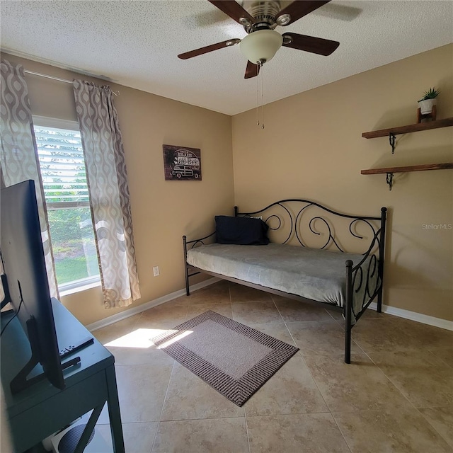 tiled bedroom featuring a textured ceiling, ceiling fan, and baseboards