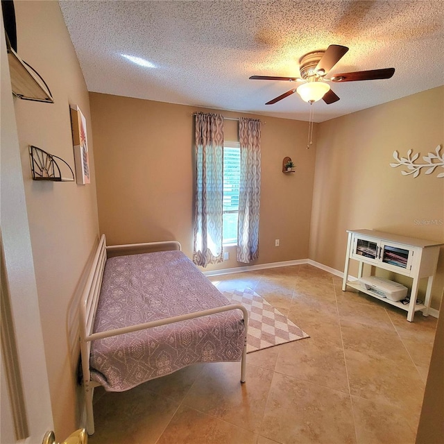 bedroom featuring a textured ceiling, tile patterned floors, ceiling fan, and baseboards