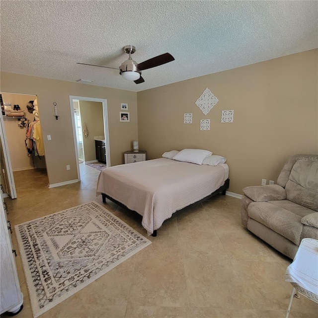 bedroom featuring a spacious closet, light tile patterned floors, a closet, ceiling fan, and a textured ceiling