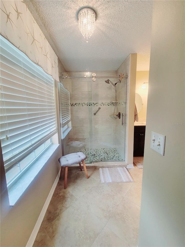 bathroom with baseboards, a textured ceiling, and a stall shower
