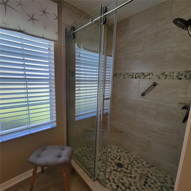 full bath featuring a shower stall and baseboards