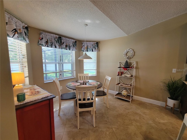 dining space with a textured ceiling and baseboards