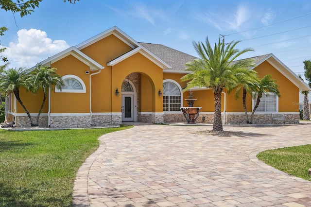 2 Cleveland Ct, Palm Coast, FL 32137 - view of front of property featuring stone siding, stucco siding, a front yard, and curved driveway