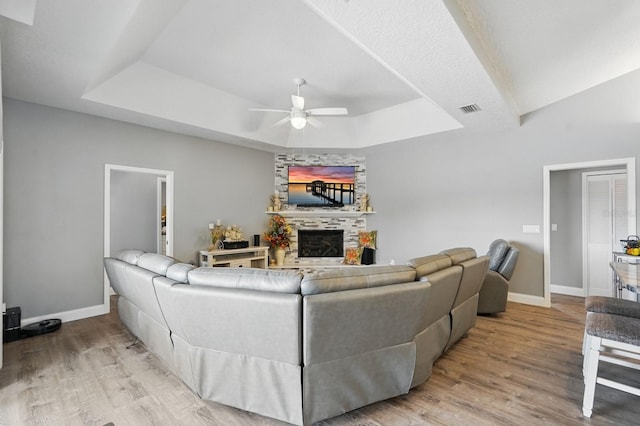 2 Cleveland Ct, Palm Coast, FL 32137 - living room featuring a tray ceiling, a ceiling fan, wood finished floors, and a large fireplace