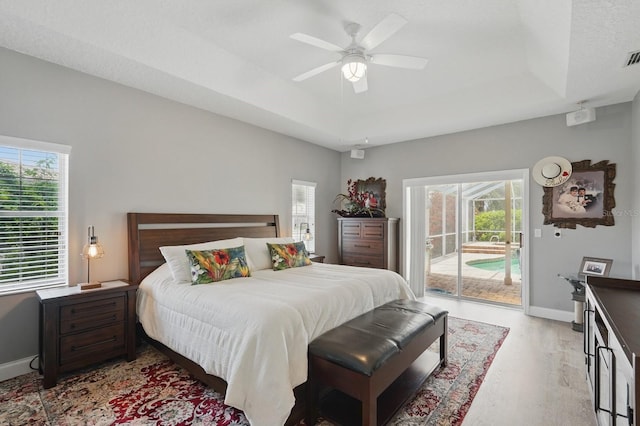2 Cleveland Ct, Palm Coast, FL 32137 - bedroom featuring access to exterior, a tray ceiling, light wood-type flooring, and multiple windows
