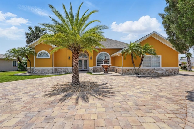 2 Cleveland Ct, Palm Coast, FL 32137 - view of front facade featuring french doors, stucco siding, stone siding, and curved driveway
