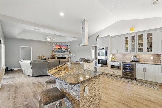 2 Cleveland Ct, Palm Coast, FL 32137 - kitchen featuring wine cooler, appliances with stainless steel finishes, light wood finished floors, lofted ceiling, and a fireplace