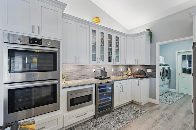 2 Cleveland Ct, Palm Coast, FL 32137 - kitchen featuring beverage cooler, appliances with stainless steel finishes, washing machine and dryer, lofted ceiling, and light stone counters