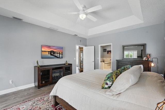 2 Cleveland Ct, Palm Coast, FL 32137 - bedroom featuring wood finished floors, a tray ceiling, a ceiling fan, and connected bathroom
