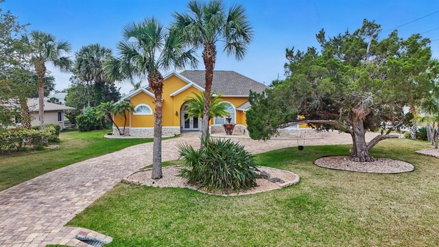 2 Cleveland Ct, Palm Coast, FL 32137 - view of property hidden behind natural elements with french doors, a front yard, stucco siding, and decorative driveway