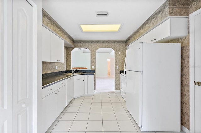 10 Eastwood Dr, Palm Coast, FL 32164 - kitchen featuring white appliances, dark countertops, arched walkways, light tile patterned flooring, and a sink