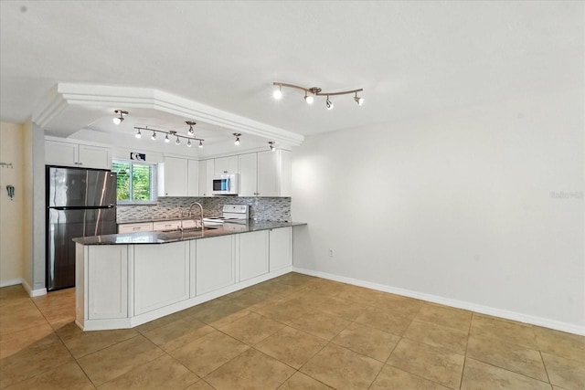 120 Oak Ln, Flagler Beach, FL 32136 - kitchen with white appliances, a peninsula, a sink, white cabinets, and backsplash