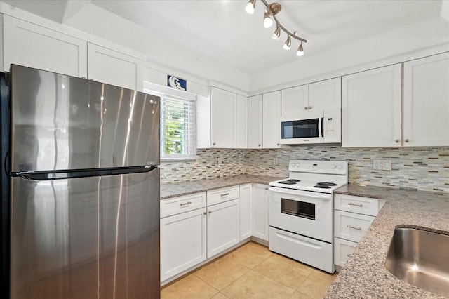 120 Oak Ln, Flagler Beach, FL 32136 - kitchen with white appliances, light tile patterned floors, tasteful backsplash, and white cabinets