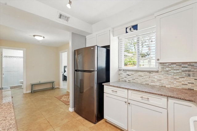 120 Oak Ln, Flagler Beach, FL 32136 - kitchen featuring freestanding refrigerator, decorative backsplash, white cabinets, light tile patterned flooring, and light stone counters