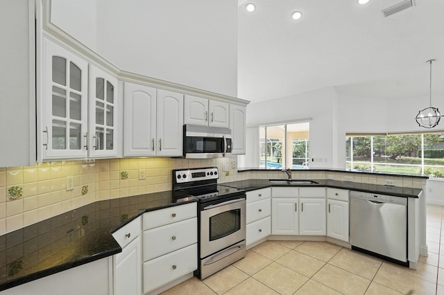 47 Old Oak Dr S, Palm Coast, FL 32137 - kitchen with stainless steel appliances, a peninsula, a sink, light tile patterned flooring, and glass insert cabinets