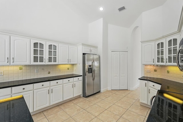 47 Old Oak Dr S, Palm Coast, FL 32137 - kitchen featuring stainless steel fridge, high vaulted ceiling, arched walkways, glass insert cabinets, and white cabinets