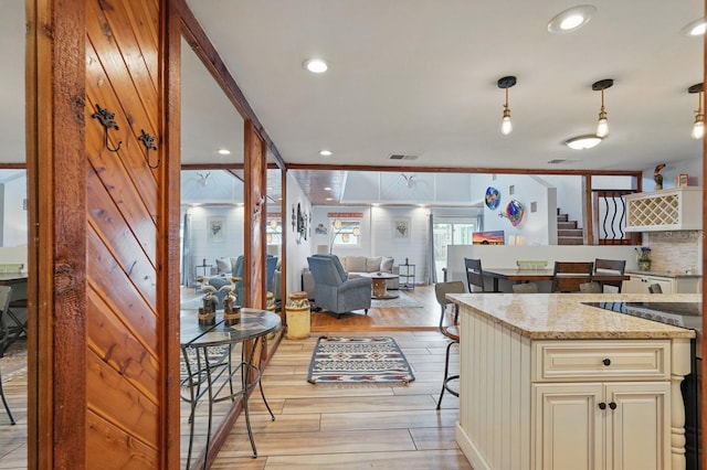 1819 S Flagler Ave, Flagler Beach, FL 32136 - kitchen featuring cream cabinets, light wood-style floors, light stone countertops, ornamental molding, and open floor plan