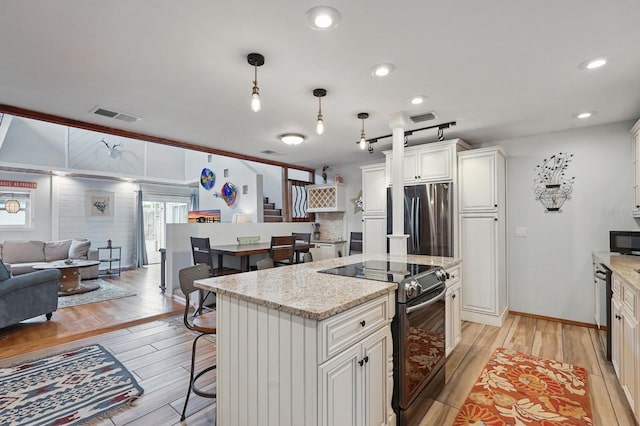 1819 S Flagler Ave, Flagler Beach, FL 32136 - kitchen with stainless steel appliances, light wood-style floors, a kitchen breakfast bar, a center island, and light stone counters
