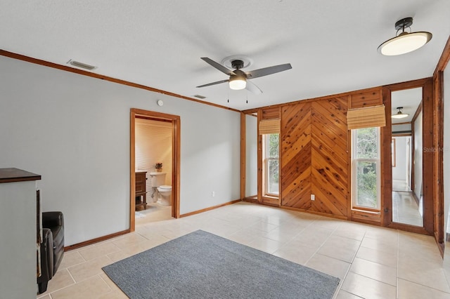1819 S Flagler Ave, Flagler Beach, FL 32136 - empty room featuring light tile patterned floors, ceiling fan, baseboards, ornamental molding, and wood walls