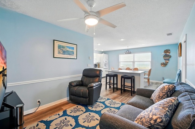 7029 N Ocean Shore Blvd, Palm Coast, FL 32137 - living room with a textured ceiling, a ceiling fan, light wood-style floors, baseboards, and recessed lighting