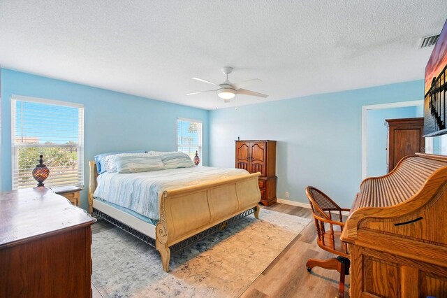 7029 N Ocean Shore Blvd, Palm Coast, FL 32137 - bedroom featuring light wood-style flooring, a ceiling fan, a textured ceiling, and baseboards