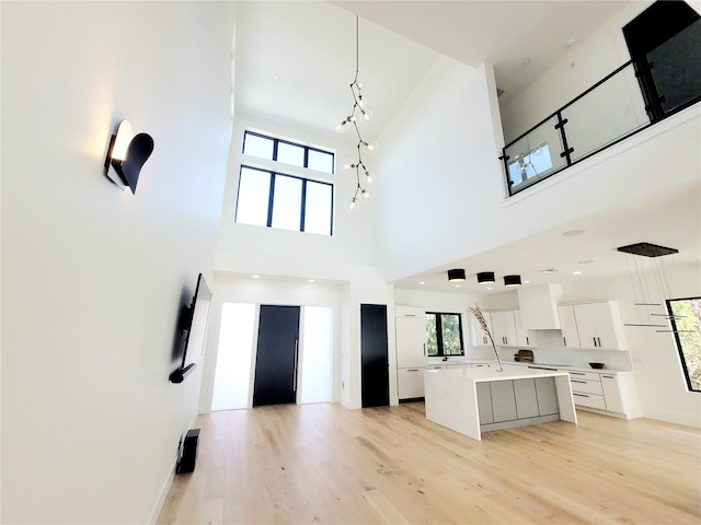 807 N Flagler Ave, Flagler Beach, FL 32136 - unfurnished living room featuring light wood-style flooring, a high ceiling, and baseboards