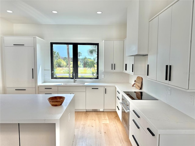 807 N Flagler Ave, Flagler Beach, FL 32136 - kitchen featuring black electric stovetop, a sink, stainless steel oven, light wood-type flooring, and dishwashing machine