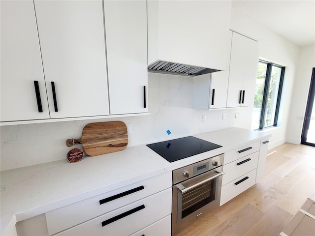 807 N Flagler Ave, Flagler Beach, FL 32136 - kitchen featuring stainless steel oven, black electric cooktop, decorative backsplash, and white cabinets