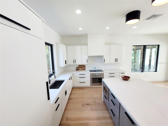 807 N Flagler Ave, Flagler Beach, FL 32136 - kitchen with a sink, stainless steel oven, black electric stovetop, white cabinets, and recessed lighting