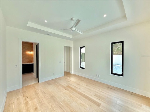 807 N Flagler Ave, Flagler Beach, FL 32136 - unfurnished bedroom featuring a tray ceiling, light wood-type flooring, baseboards, connected bathroom, and recessed lighting
