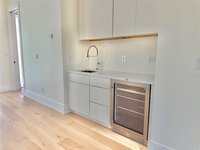807 N Flagler Ave, Flagler Beach, FL 32136 - bar area with wine cooler, a sink, light wood-style flooring, and baseboards